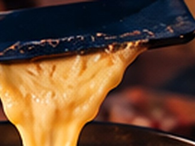 Fromage à raclette fondu qui coule d’un poêlon